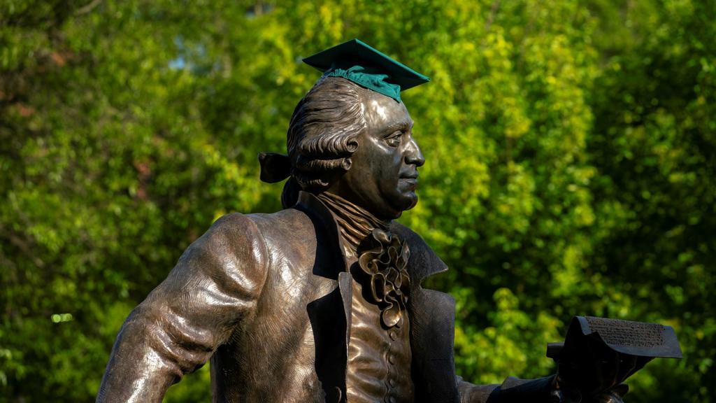 The George Ƶ statue wears a green graduation cap.